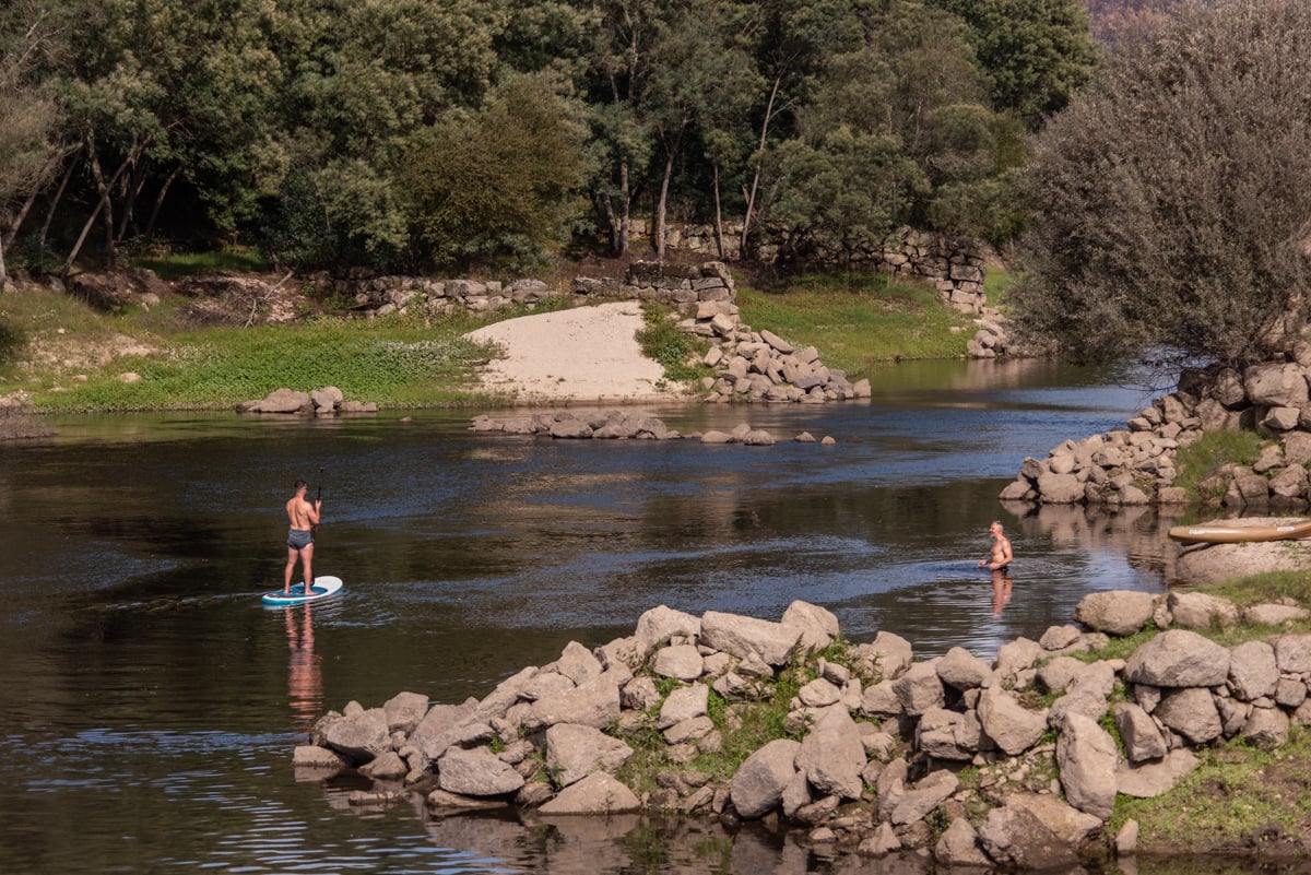 A man paddle-boarding down a river